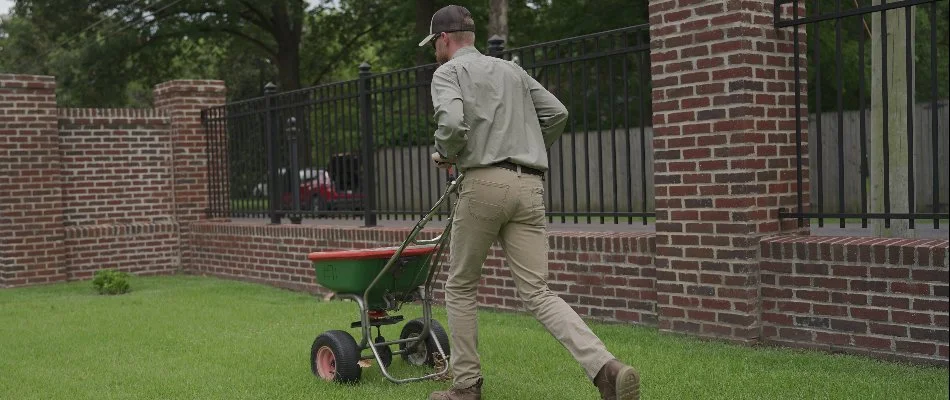 Lawn care professional applying granular fertilizer on a lawn in Memphis, TN.