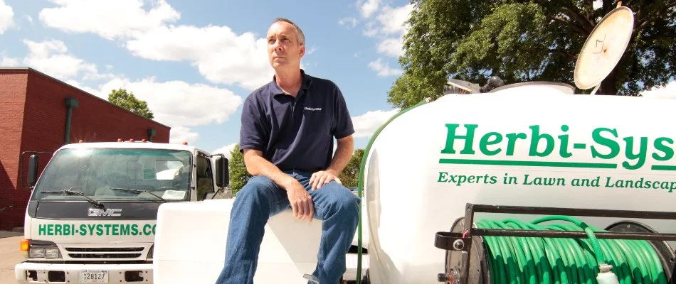 Expert in lawn fertilization in Memphis, TN, sitting near lawn care equipment.