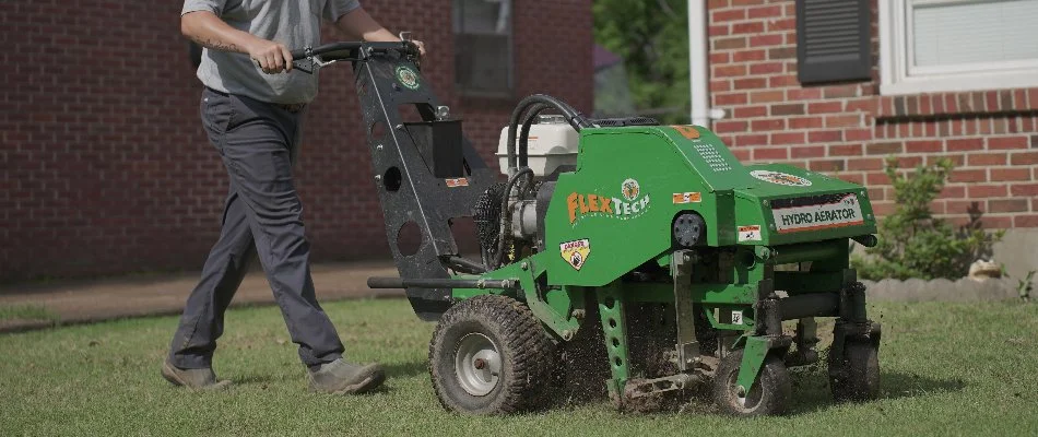 Man operating an aerator machine on a lawn in Memphis, TN.