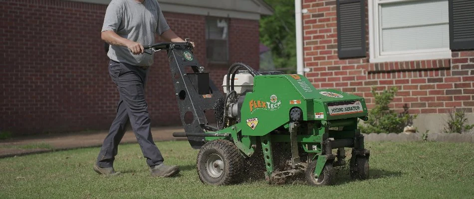 Worker performing core aeration on a lawn in Memphis, TN.