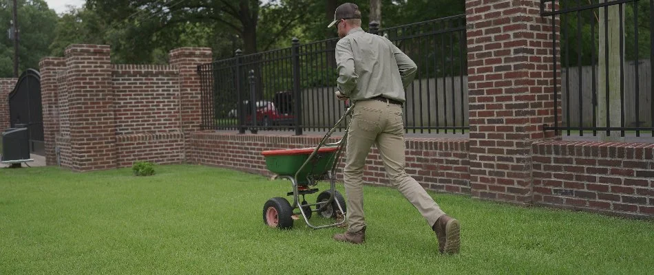 Worker pushing a fertilizer spreader on a property in Memphis, TN.