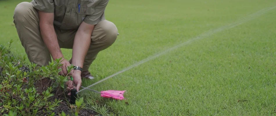 Professional adjusting a sprinkler head by a lawn in Piperton, TN.