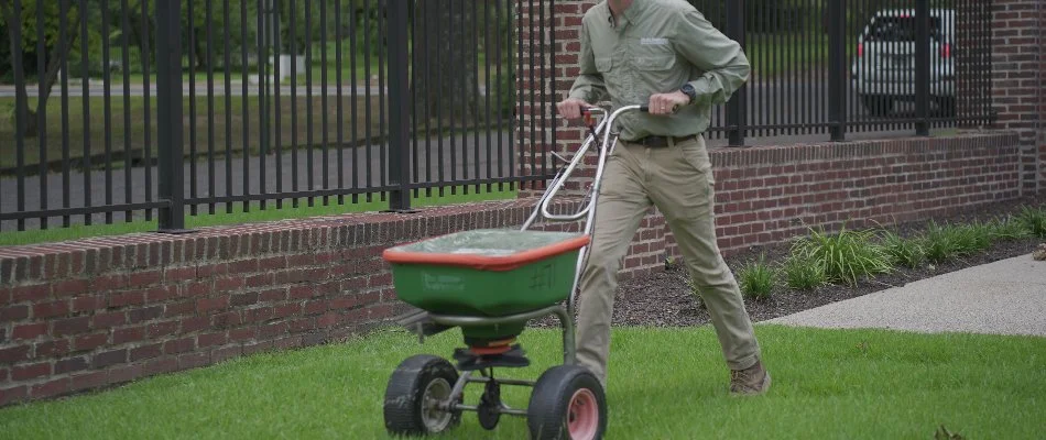 Worker applying a granular fertilizer treatment on a lawn in Memphis, TN.